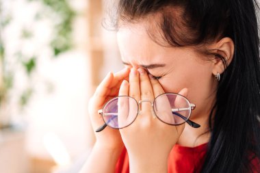 Çekici bir kız. Yakın plan. Elinde gözlüklerle. Zavallı genç kızın görme sorunları var. O yorucu bir şekilde burnunu ve gözlerini ovuşturur. Gözlüklere odaklan..