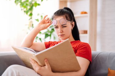Gözlüklü genç bir esmer evde görme sorunu olan bir kitap okuyor. Görme sorunu ya da göz yorgunluğu çeken bir öğrenci kitap okumaktadır.
