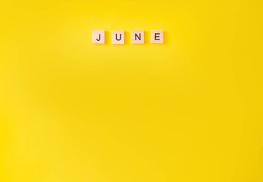 Sözcük haziran, tahta harflerle yazılmış. Dizaynınız için sarı arkaplan üzerine haziran metni, üst görünüm konsepti. metin için yer