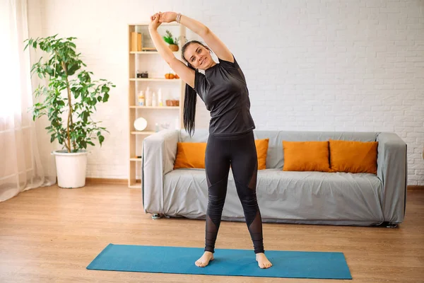 Spor üniformalı genç bir kız antrenman yapıyor ve esniyor, evde egzersiz yapıyor, bilgisayarda spor videoları izliyor..