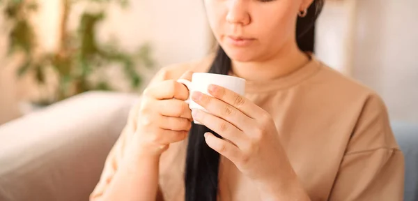 a young girl with a cup of coffee at home on the couch. The concept of comfort. close-up.