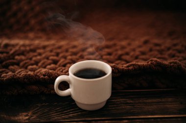 Kahverengi örgü bir ekosenin arka planında bir fincan kahve. Ev konforu kavramı.