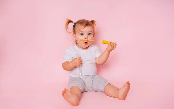 一个有着粉色背景的可爱的小女孩的画像 一个儿童模特儿吹肥皂泡 玩得很开心 儿童用品广告 — 图库照片