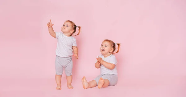 Två Åriga Tvillingflickor Tittar Upp Isolerade Rosa Bakgrund Reklam För — Stockfoto