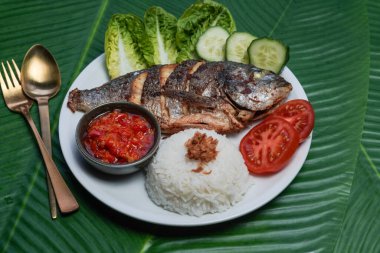 Buharda pilav, sebze ve sambal ile servis edilen Endonezya kızarmış balığı.