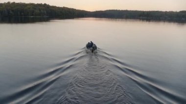 People in motorboat on lake at sunrise, North Bay, Ontario, Canada
