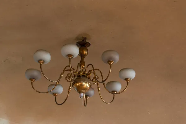 Sarı tavanda kirli bir avize asılı. Alt manzara, birkaç lamba, kapalı