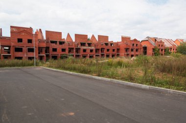 Daireler için tamamlanmamış tuğla ev. Terk edilmiş kırmızı tuğla bina. İnşaata yatırım yapan aldatılmış sermaye sahipleri