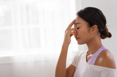 Nefesini yönlendirmek için, Asyalı bir kadın parmaklarıyla alnına dokunur. Yoga ve meditasyona başlamak için.