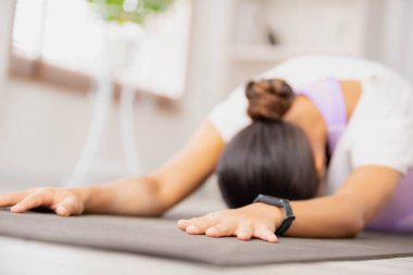 Elbiselerini giy. Spor giyim bölümünde çalışan, yoga yapan, çocuk egzersizi yapan, Balasana duruşlu bir kadın..