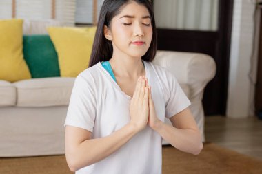 Asyalı bir kadınla sabah yogası, kolay bir pozisyonda oturmak, Sukhasana duruşu ve internette meditasyon yapmak..