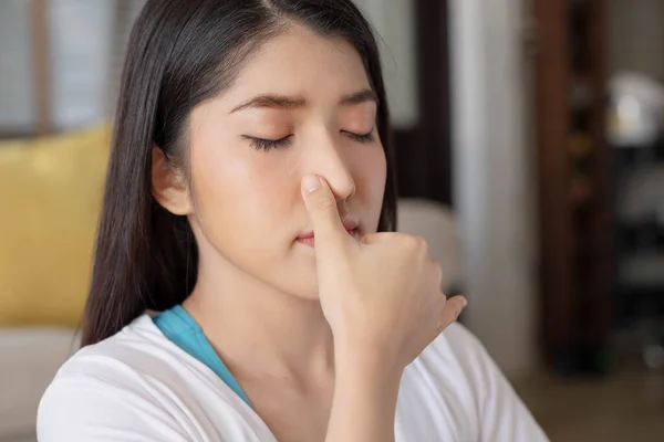 To guide her breath, an Asian lady touches her nostrils with her fingers. To get started with yoga and meditation