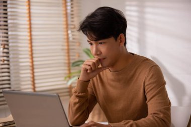 Asyalı işadamı, evde dizüstü bilgisayarla çalışmaktan yorgun ve endişeli..