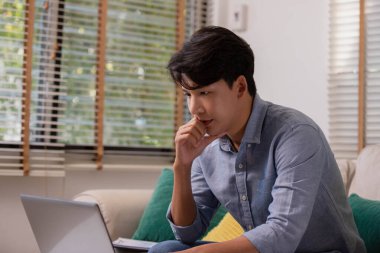 Asyalı işadamı, evde dizüstü bilgisayarla çalışmaktan yorgun ve endişeli..