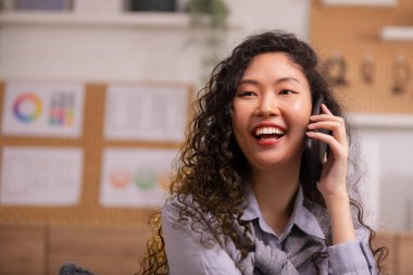 Telefon görüşmesi. Kendine güvenen Asyalı bir kadın kanepeye oturur ve konuşur.. 