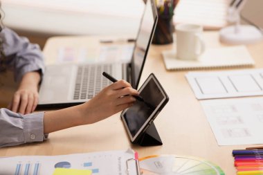 Yakın çekim. Sabah Asyalı bir tasarımcı bir tablet üzerinde çalışıyor. Çizim ve çizim yapıyor..