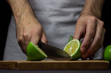 Şef ahşap bir tahtanın üzerindeki limonu keser. Ekşi meyve. Citrus meyvesi.