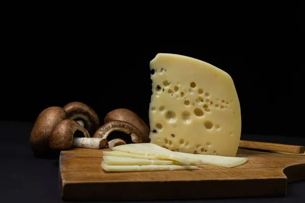 Gelber Käse Auf Schwarzem Hintergrund Scheibenkäse Neben Rohen Pilzen Auf — Stockfoto