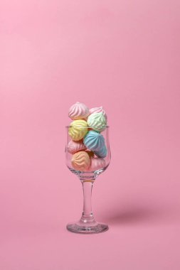 Pembe arka planda çok renkli kremalar. Dopdolu cam kadehler..
