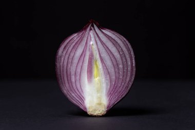 Siyah arka planda kırmızı soğan. Koyu arkaplanda yarım soğan. Soğan çeşitliliği
