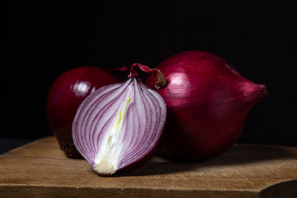 Red onion on a black background. Red onion cut in half on a board. Onion variety