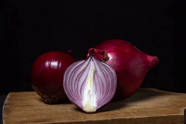 Red onion on a black background. Red onion cut in half on a board. Onion variety