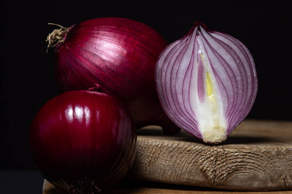 Red onion on a black background. Red onion cut in half on a board. Onion variety