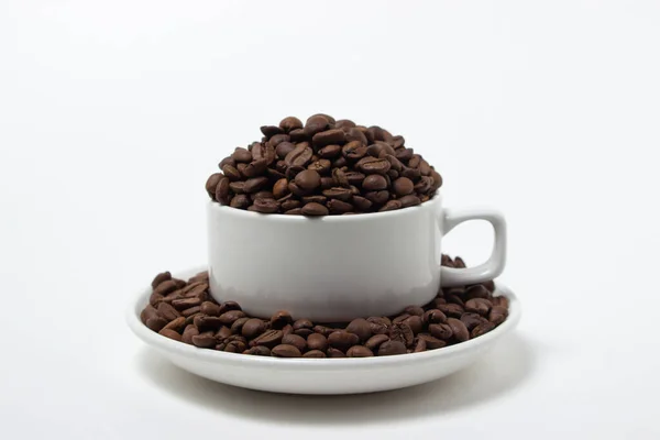 白い背景にコーヒー豆が溢れる白いカップ 焼きたてのコーヒー豆 — ストック写真