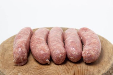Beyaz arka planda tahta bir tahtada çiğ et sosisi. Doğal kaplamalı ev yapımı sosisler. Et ürünleri