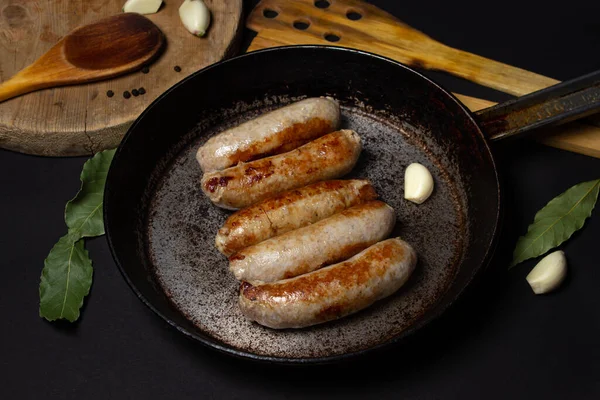 Siyah arka planda tavada kızarmış et sosisi. Doğal kaplamalı ev yapımı sosisler. Et ürünleri. Ev yemeği.