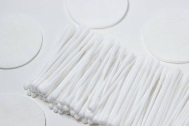 Beyaz arka planda pamuk tomurcuklar ve pamuk pedler. Temizlik ve kişisel temizlik araçları.