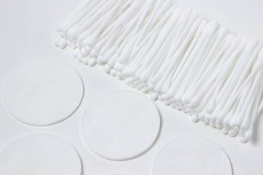 Beyaz arka planda pamuk tomurcuklar ve pamuk pedler. Temizlik ve kişisel temizlik araçları.