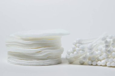 Beyaz arka planda pamuk tomurcuklar ve pamuk pedler. Temizlik ve kişisel temizlik araçları.