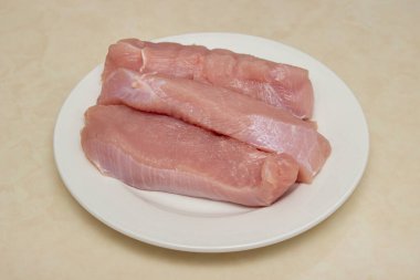 Mutfak masasında çiğ hindi bifteği. Tabakta hindi göğsü filetosu. Diyet et