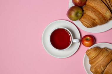 Beyaz bir masada lezzetli ve sağlıklı bir kahvaltı. Bir fincan çay, hamur işi ve meyveli..