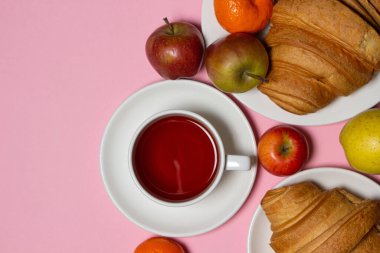 Beyaz bir masada lezzetli ve sağlıklı bir kahvaltı. Bir fincan çay, hamur işi ve meyveli..