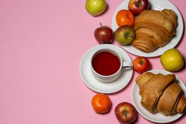 Beyaz bir masada lezzetli ve sağlıklı bir kahvaltı. Bir fincan çay, hamur işi ve meyveli..