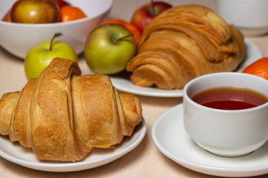 Beyaz bir masada lezzetli ve sağlıklı bir kahvaltı. Bir fincan çay, hamur işi ve meyveli..