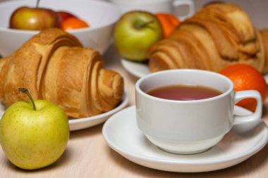 Beyaz bir masada lezzetli ve sağlıklı bir kahvaltı. Bir fincan çay, hamur işi ve meyveli..