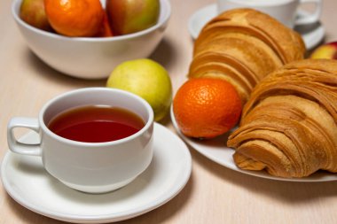 Beyaz bir masada lezzetli ve sağlıklı bir kahvaltı. Bir fincan çay, hamur işi ve meyveli..