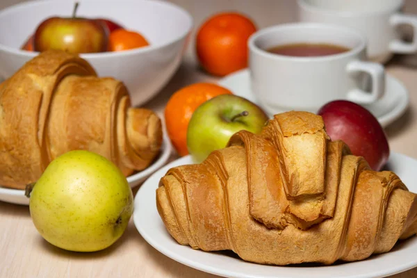 Beyaz bir masada lezzetli ve sağlıklı bir kahvaltı. Bir fincan çay, hamur işi ve meyveli..