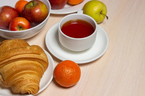 Beyaz bir masada lezzetli ve sağlıklı bir kahvaltı. Bir fincan çay, hamur işi ve meyveli..