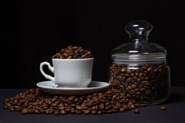 Siyah arka planda kahve çekirdekleri. Kahve çekirdeği dolu bir kahve fincanı. Büyük boy kafein.