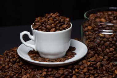 Siyah arka planda kahve çekirdekleri. Kahve çekirdeği dolu bir kahve fincanı. Büyük boy kafein.