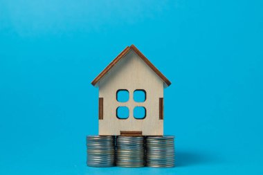 Mavi arka planda paraların üzerinde ahşap bir ev. Emlak alım ve satım konsepti. Emlak hizmetleri