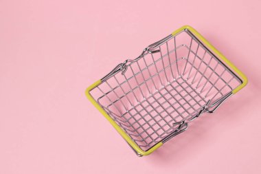 Pembe arka planda metal alışveriş sepeti. Oyuncak alışveriş sepeti. Süpermarket alışveriş kavramı.