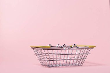 Pembe arka planda metal alışveriş sepeti. Oyuncak alışveriş sepeti. Süpermarket alışveriş kavramı.
