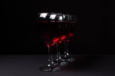 Siyah arka planda üç kadeh kırmızı şarap. Alkolik içki..