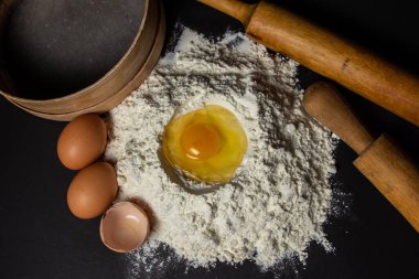Siyah arka planda un içinde çiğ yumurta. Hamur hazırlığı. Ev yapımı pişirme