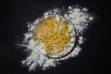 Siyah arka planda un içinde yumurtalı şehriye. Tahtada ev yapımı kuru erişte. Geleneksel makarna